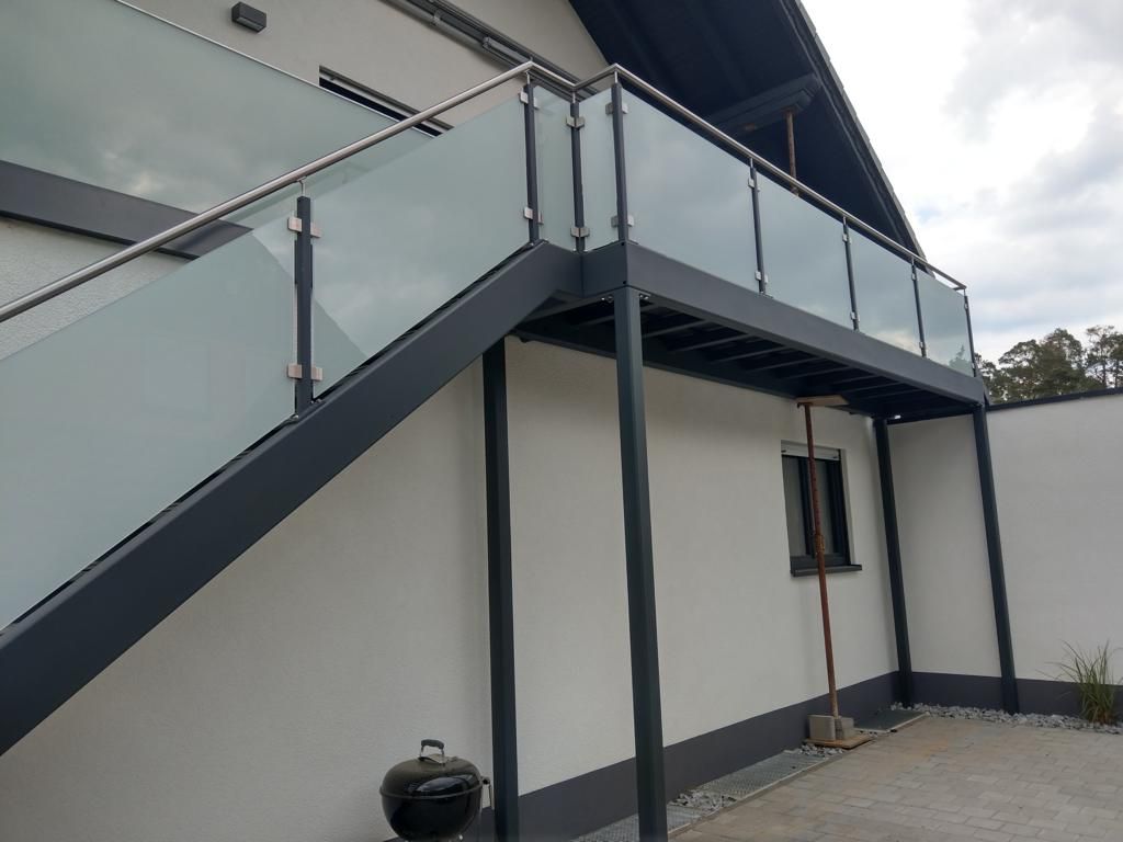 Nachträglich montierter Laubengang/Balkon an einem Wohnhaus, mit Metalltreppen in den Garten und Milchglas als Sichtschutz
