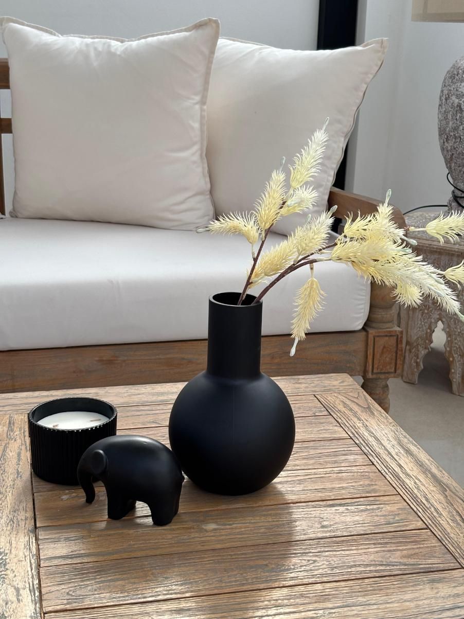 Decoración minimalista para la sala de estar sobre una mesa rústica de madera con un jarrón negro y una vela