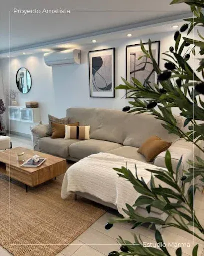 Luminoso salón moderno con sofá beige, mesa de centro de madera, alfombra tejida y plantas junto a la pared.