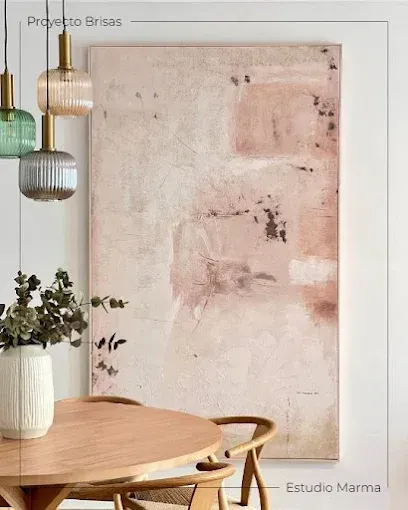 Comedor minimalista con mesa redonda de madera, sillas de mimbre, planta y un gran cuadro abstracto rosa en la pared.