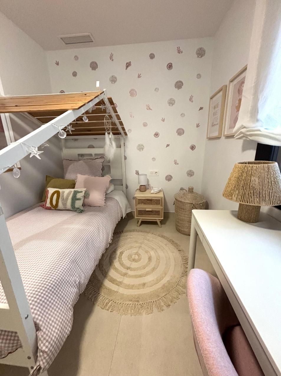 Acogedora habitación infantil con cama tipi, alfombra estampada, escritorio blanco y detalles en rosa suave.