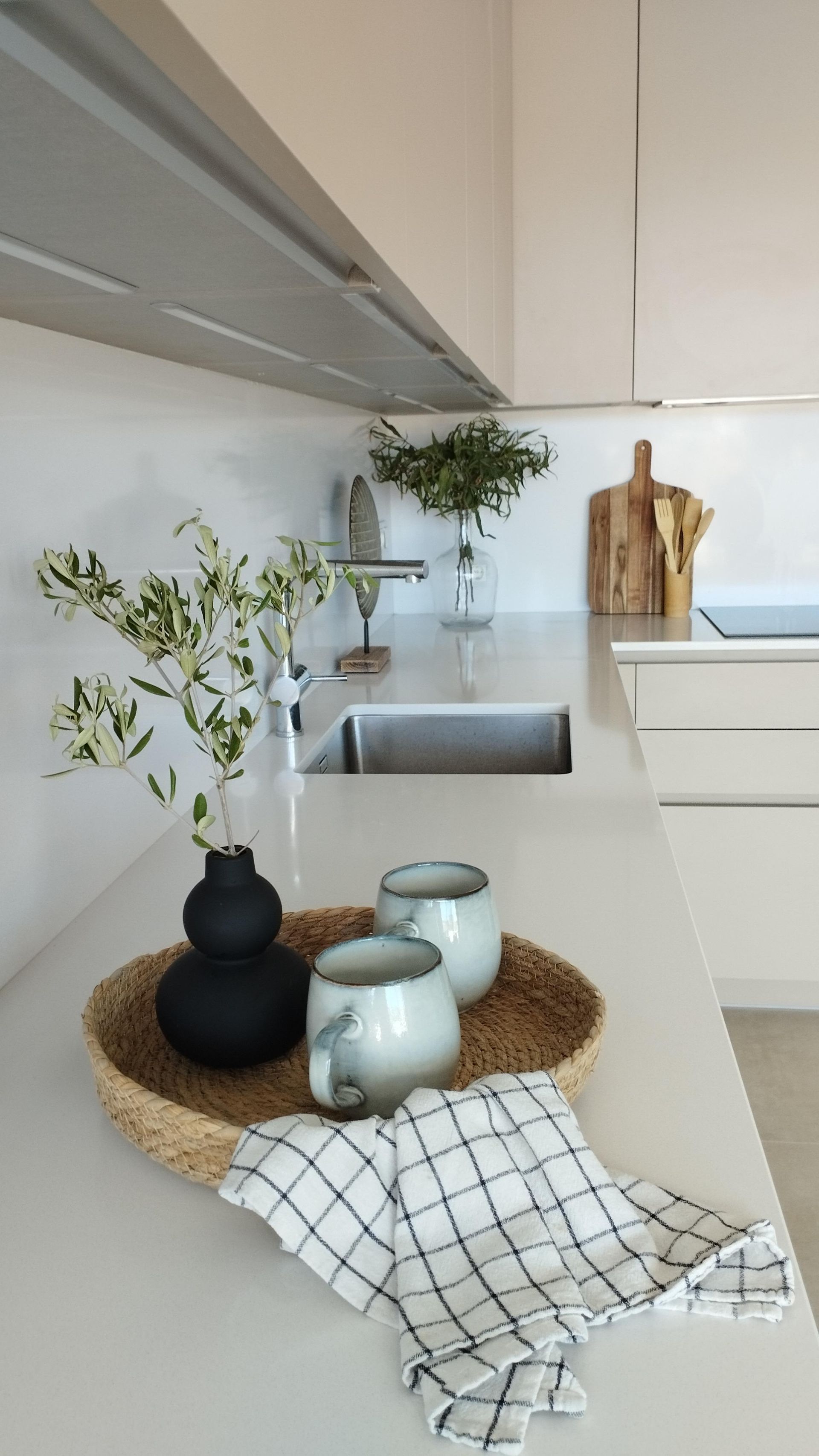 Luminoso salón con sofá beige, mesa de centro de madera, alfombra tejida y ventanas altas con cortinas transparentes.