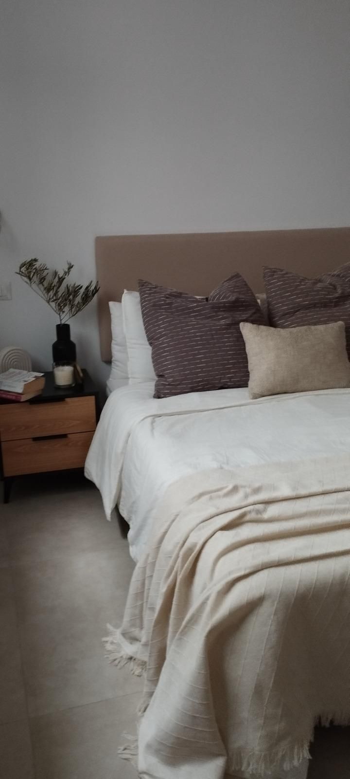 Cama bien hecha con sábanas y almohadas blancas en un dormitorio minimalista.