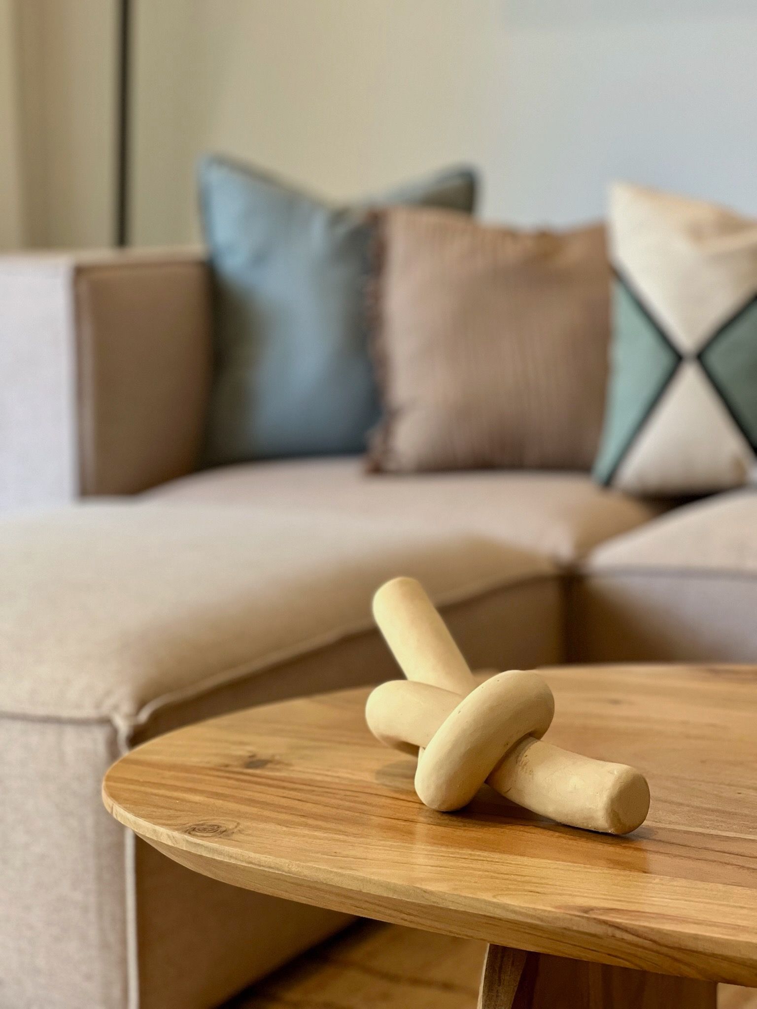 Un juguete de madera sobre una mesa de centro frente a un sofá beige con cojines azules y tostados.
