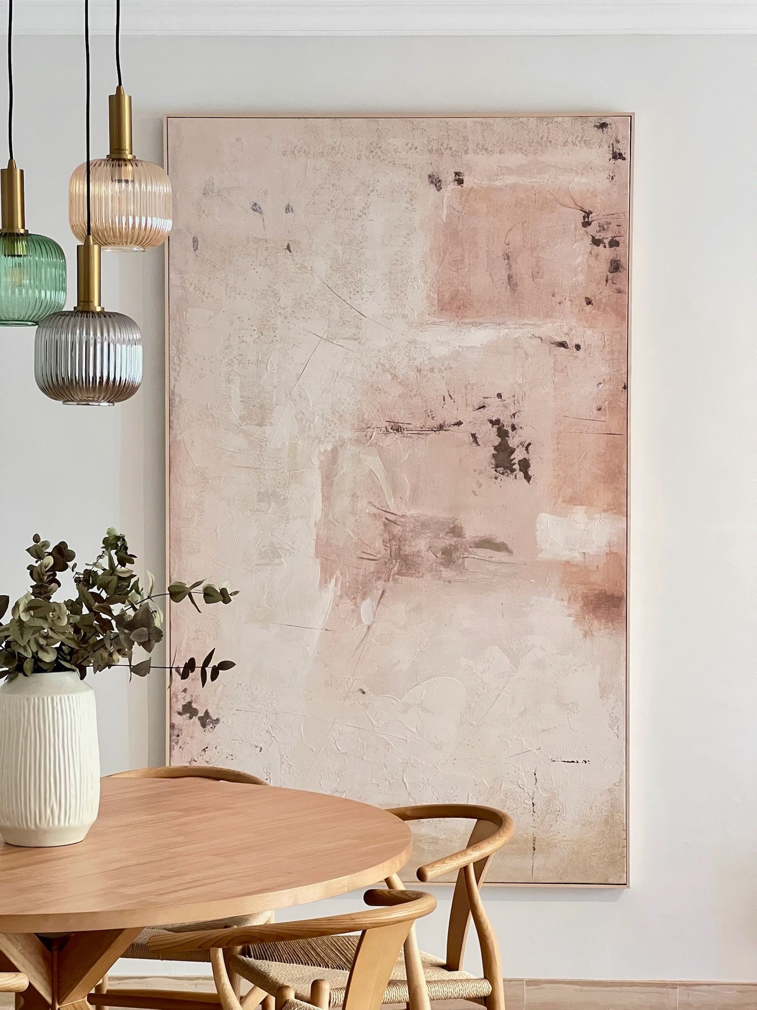 Sala de estar moderna y luminosa con sofá modular beige, mesa de centro de madera, lámpara de pie y cuadros en la pared.