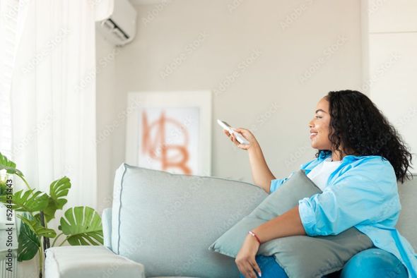 Une femme qui allume sa climatisation