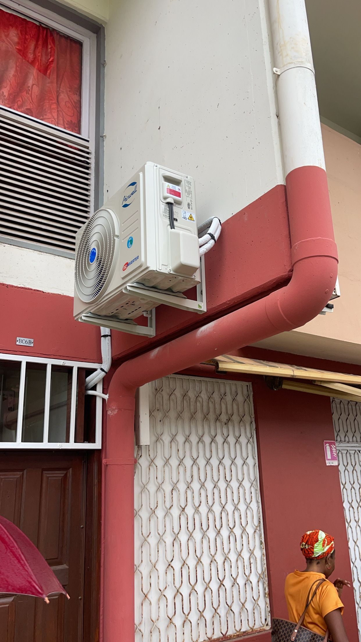 Installation de groupe extérieur de climatisation sur une façade rouge