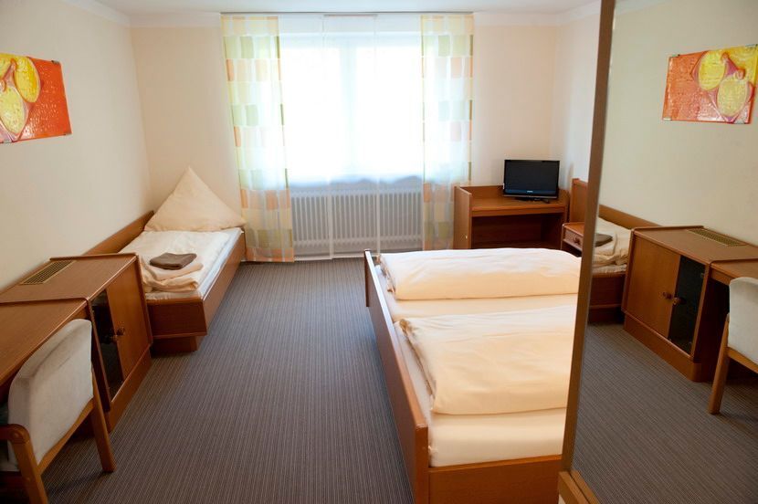 Hotelzimmer mit zwei Einzelbetten, Schreibtisch, Fernseher, Fenster und dekorativer Kunst.