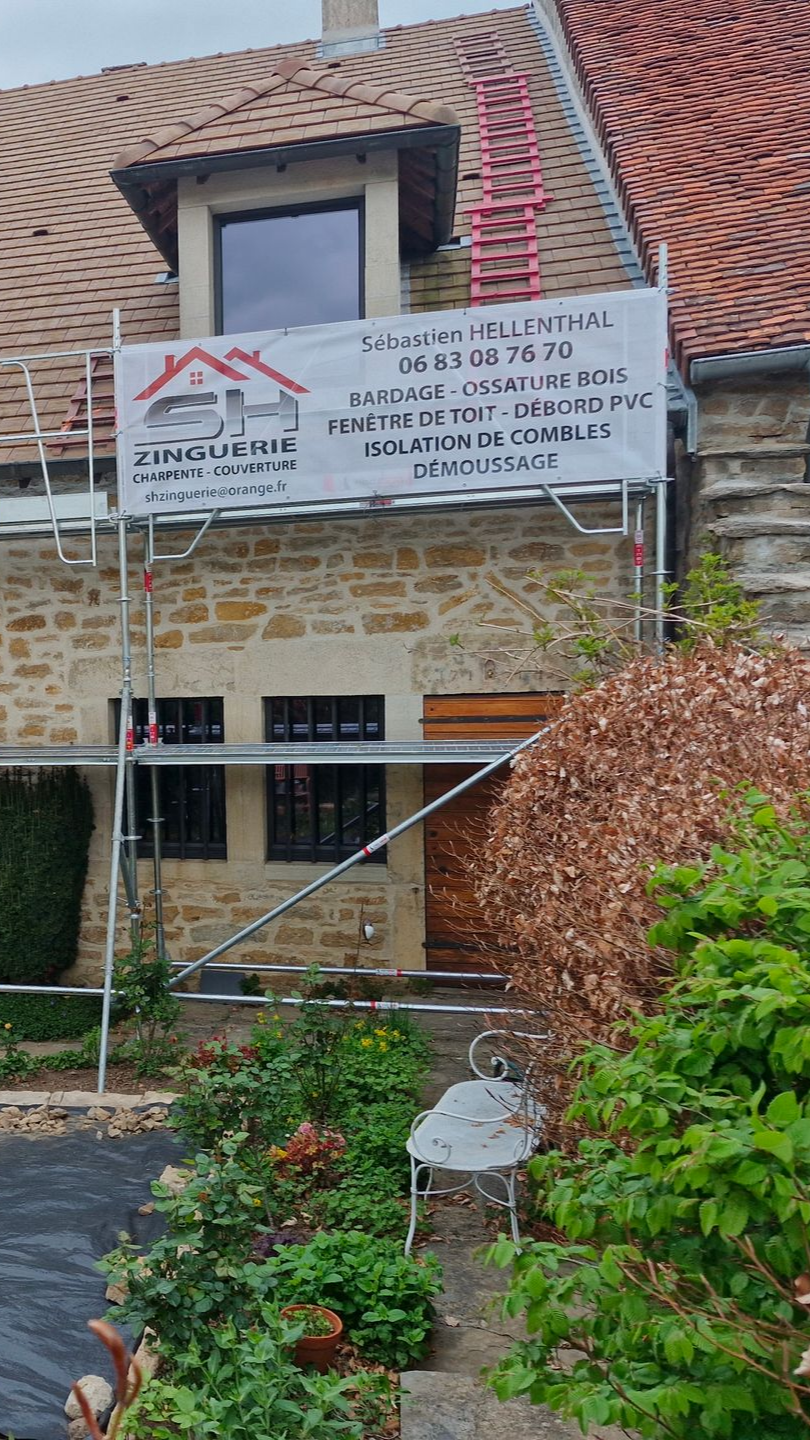 Échafaudage à côté d'une maison en pierre avec une bannière. Réparation du toit en cours.
