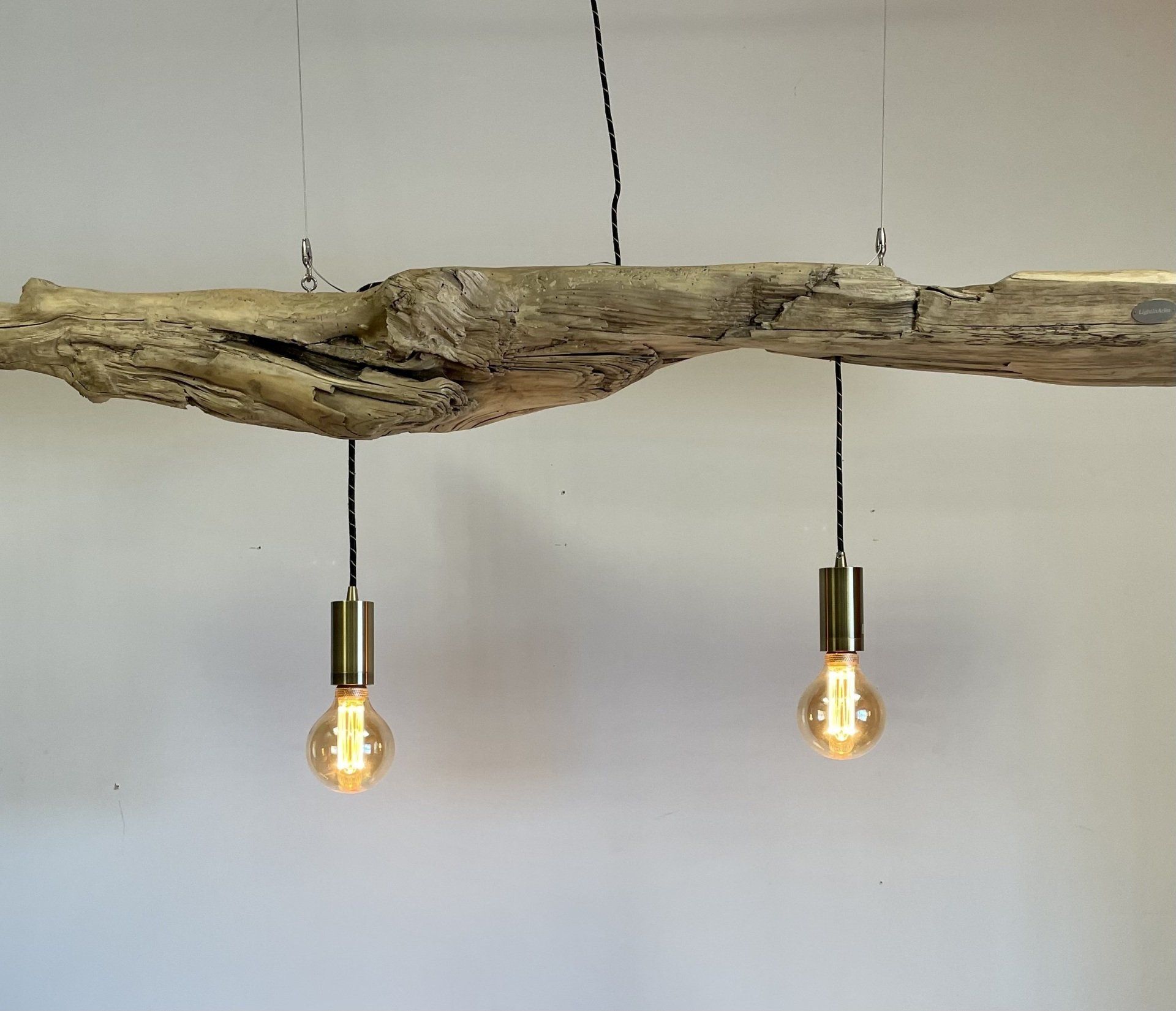 Lustre aux deux ampoules sur fond gris.