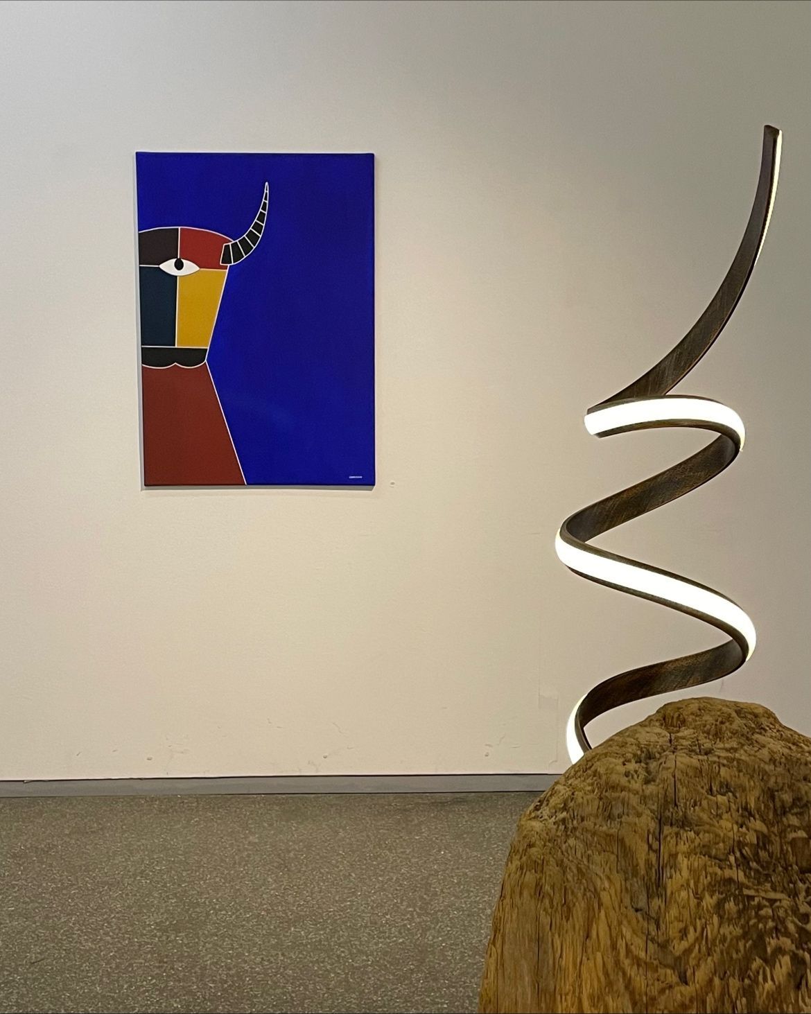 Luminaire en forme de serpentin devant un tableau.