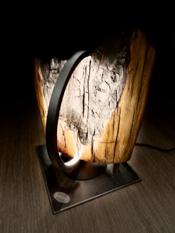 Luminaire circulaire entourant une belle pièce de bois.
