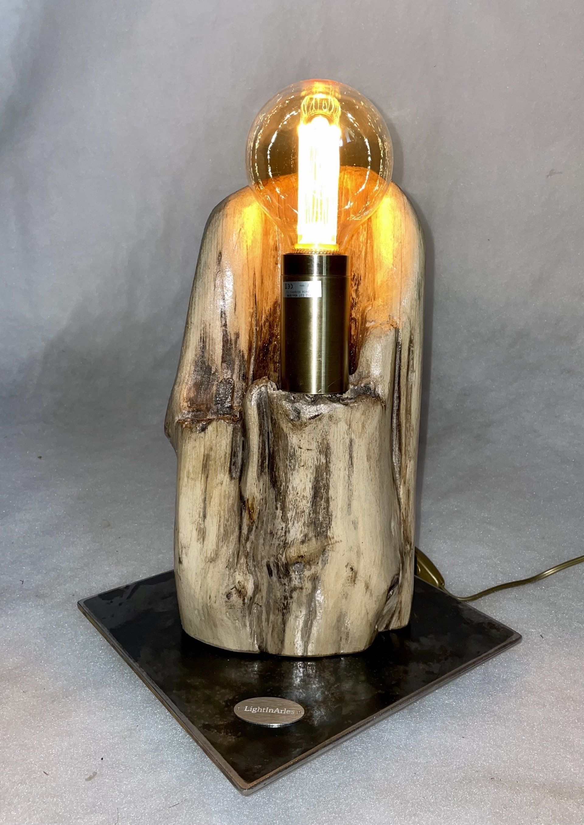 Luminaire au bois flotté avec une ampoule au milieu.