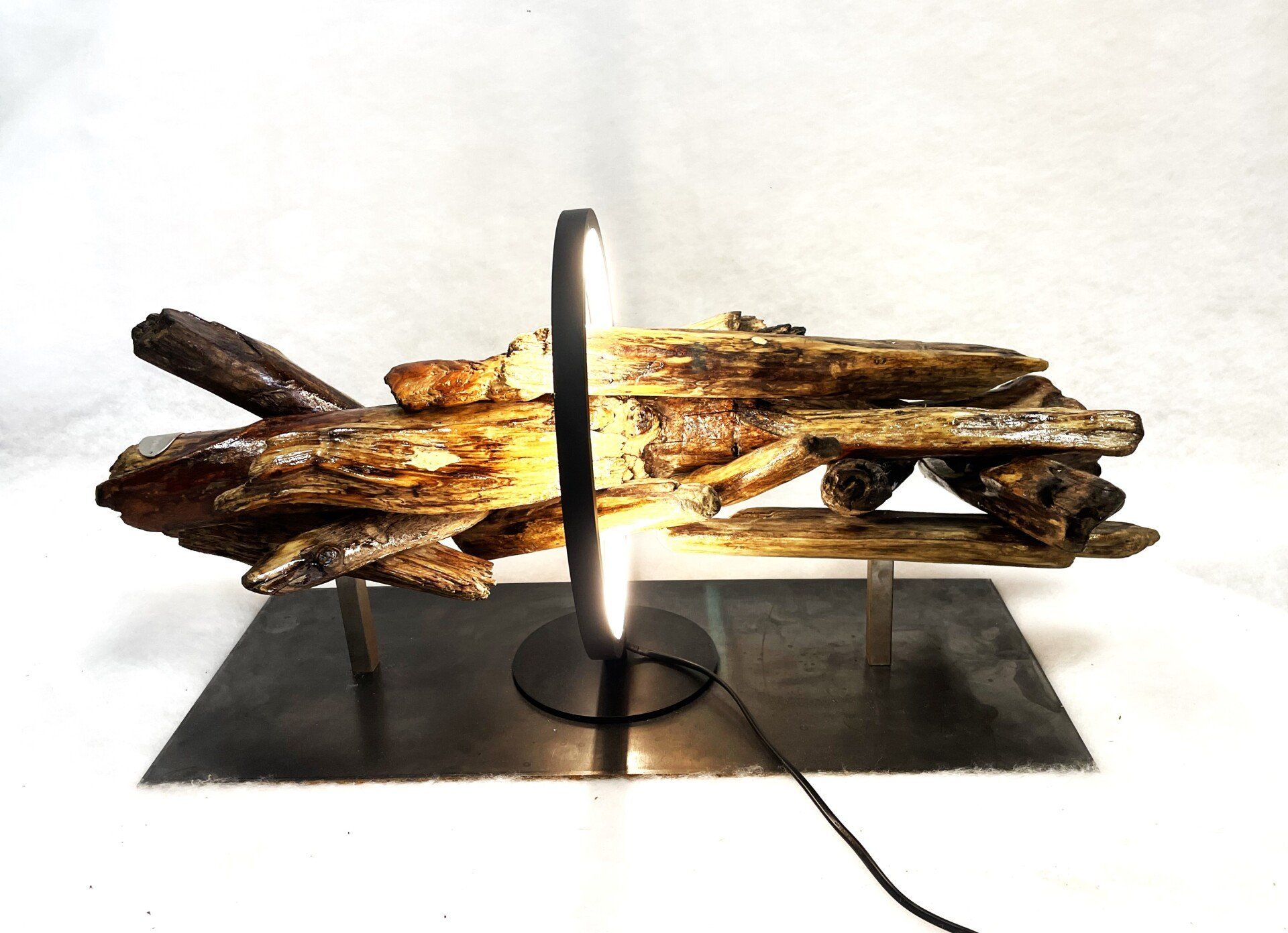 Morceaux de bois flotté entourés d'un luminaire circulaire.