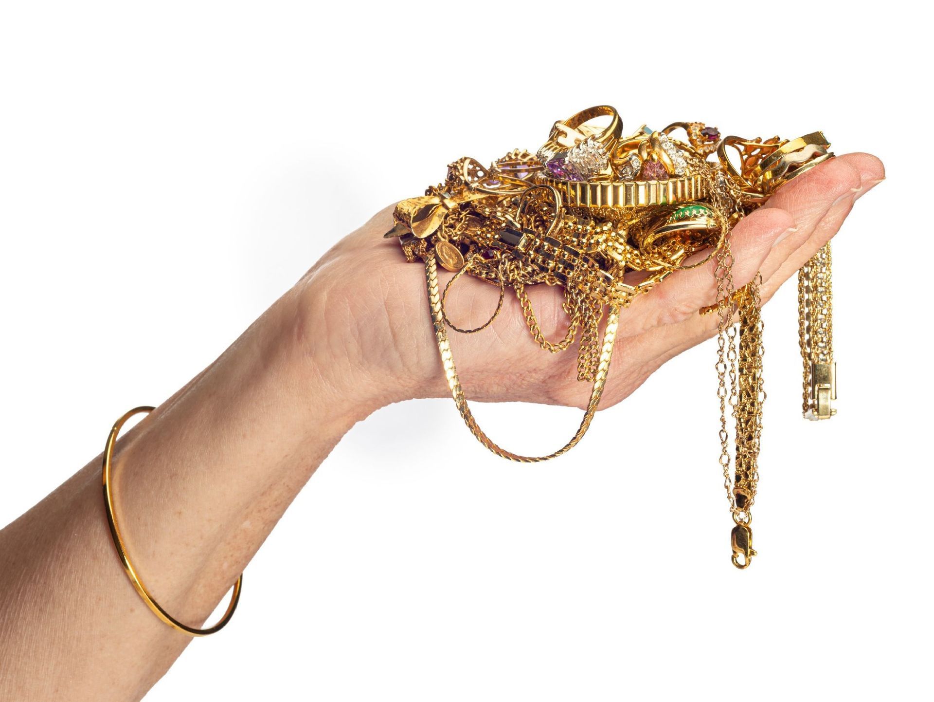 Una persona sostiene una pila de joyas de oro en su mano.