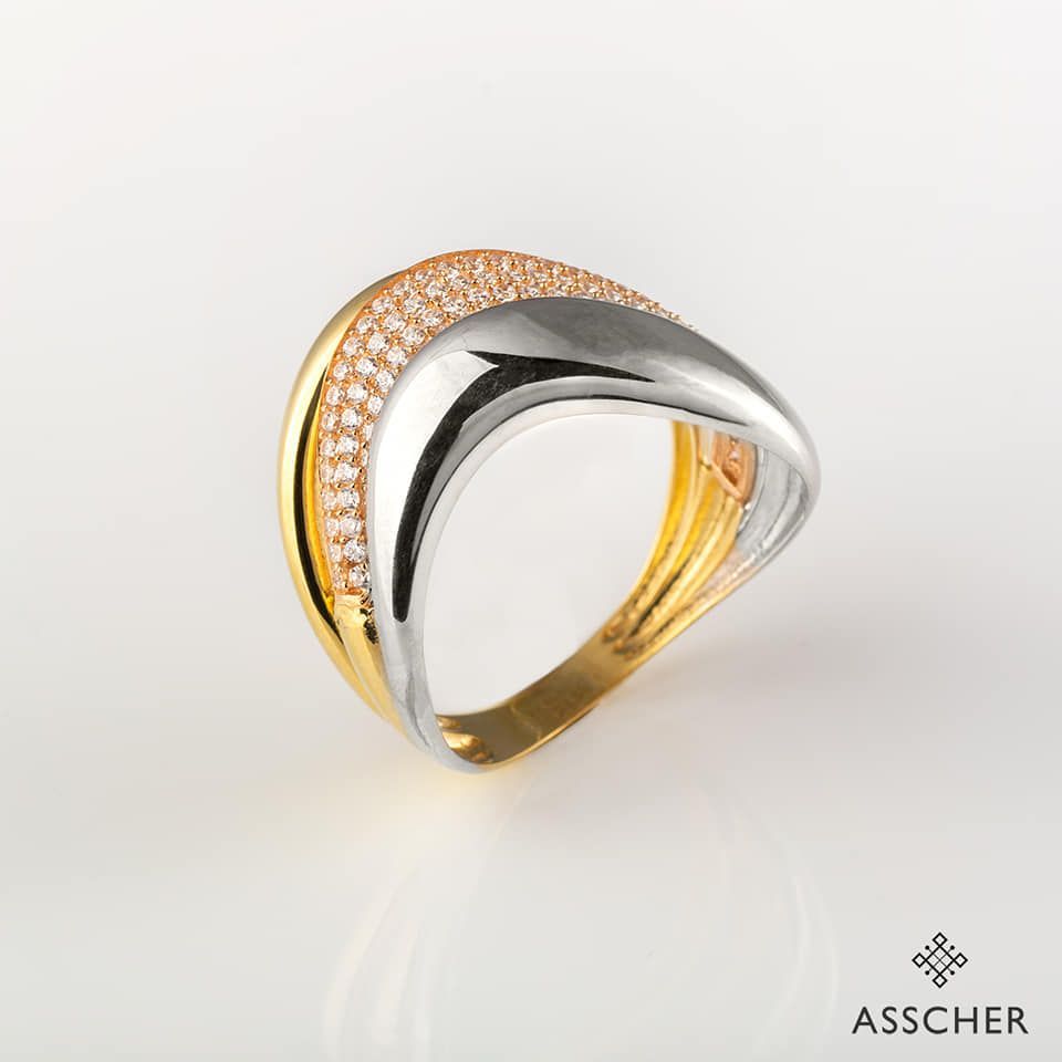 Un anillo de oro y plata de Asscher sobre una superficie blanca.