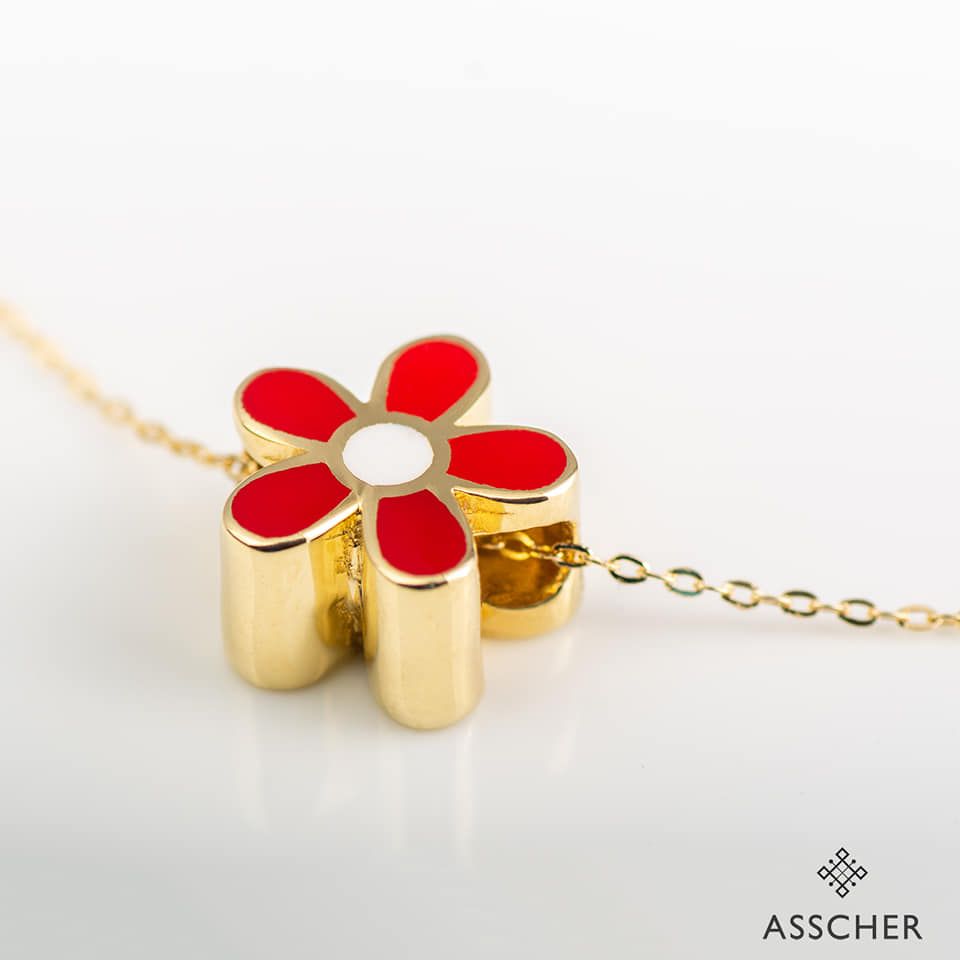 Un collar de oro con un colgante en forma de flor roja.