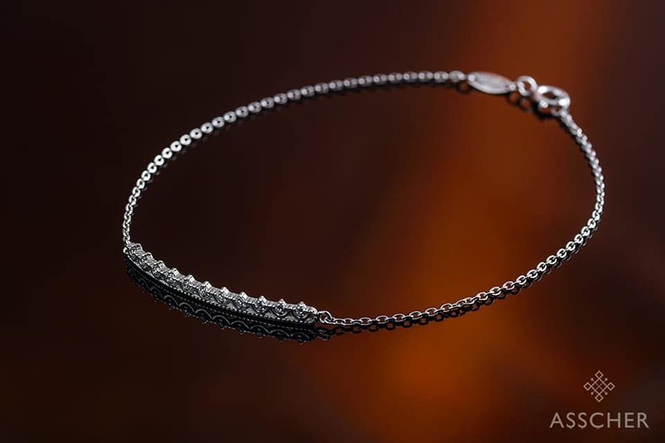 Una pulsera de plata con diamantes está sobre una mesa.