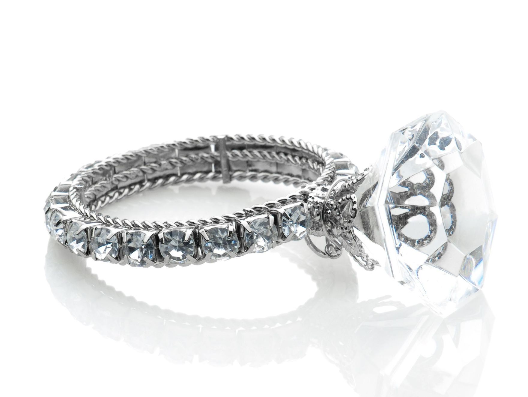 Un anillo de plata con un diamante transparente en el centro sobre una superficie blanca.