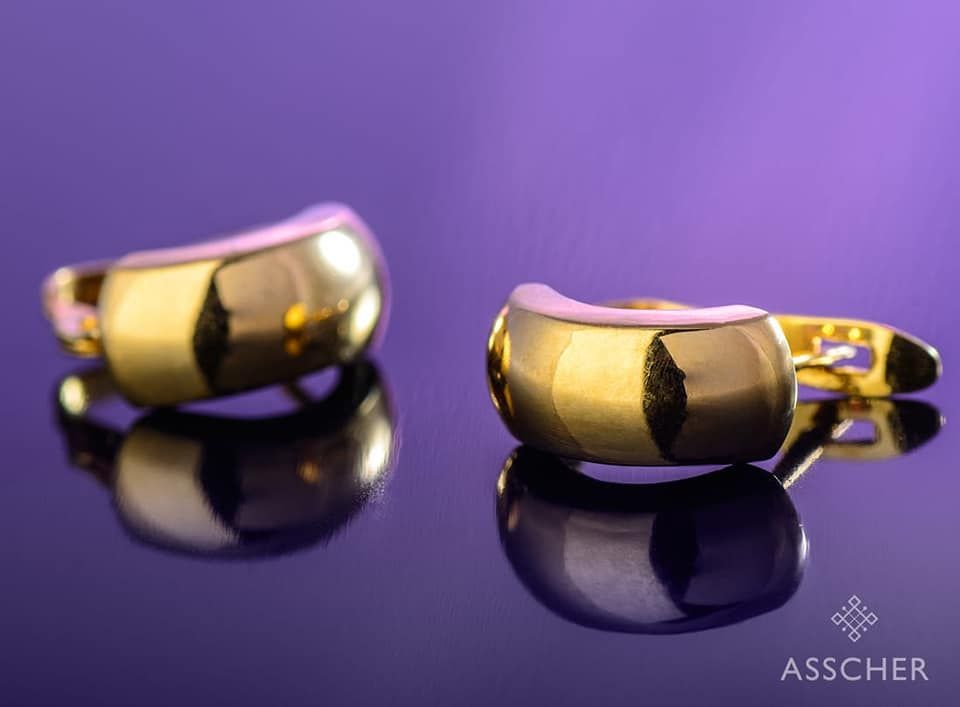 Un par de gemelos de oro sobre una superficie morada.