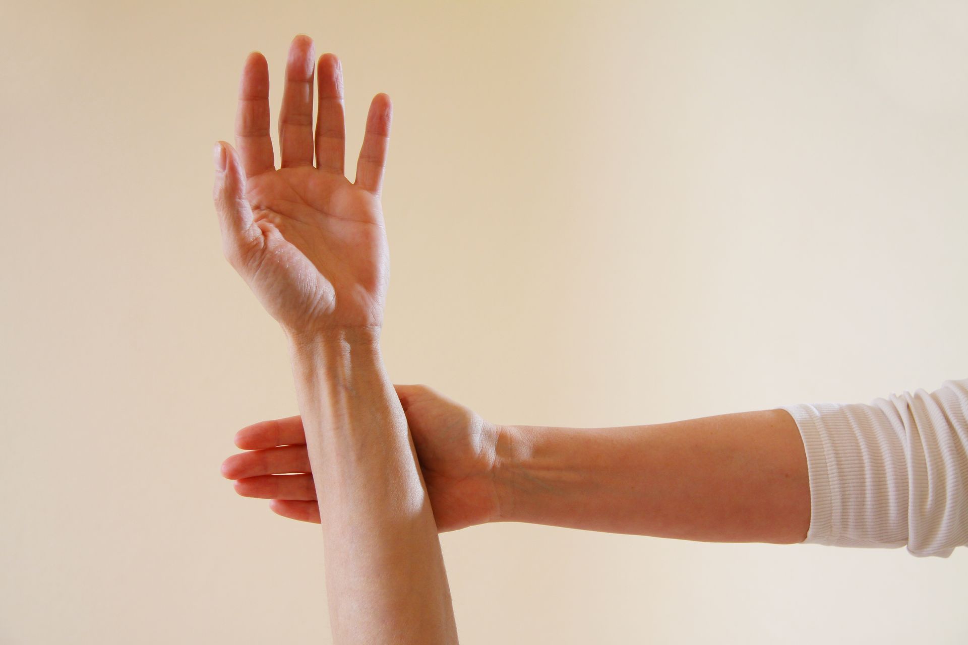 Une personne tient son avant-bras avec sa main opposée.