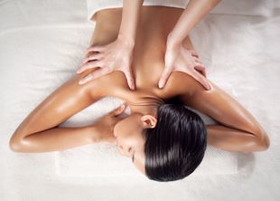 Une personne allongée sur le ventre sur une table de massage, recevant un massage du dos à l'huile.