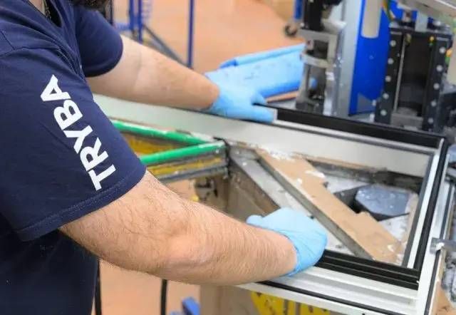 Ouvrier assemblant un cadre métallique avec des gants à un poste de travail en usine