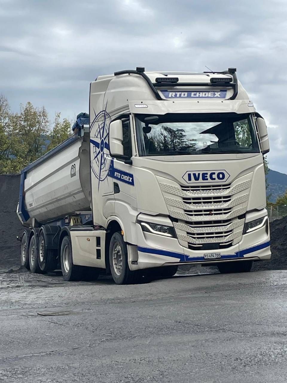 Un camion-benne blanc est garé sur le bord de la route.