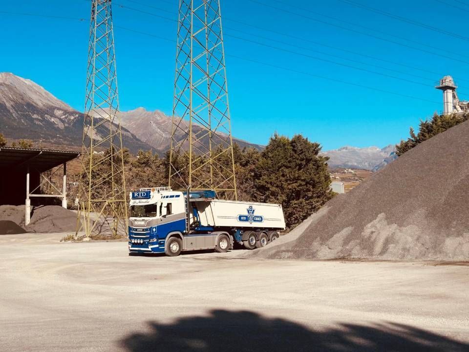 Un camion à benne basculante est garé devant un tas de terre.
