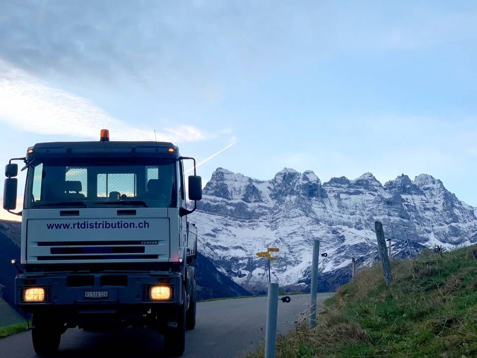 Un camion roule sur une route avec des montagnes en arrière-plan