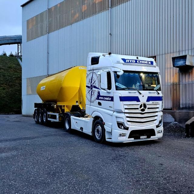 Un camion roule sur un chemin de terre à côté d'un tas de rochers.