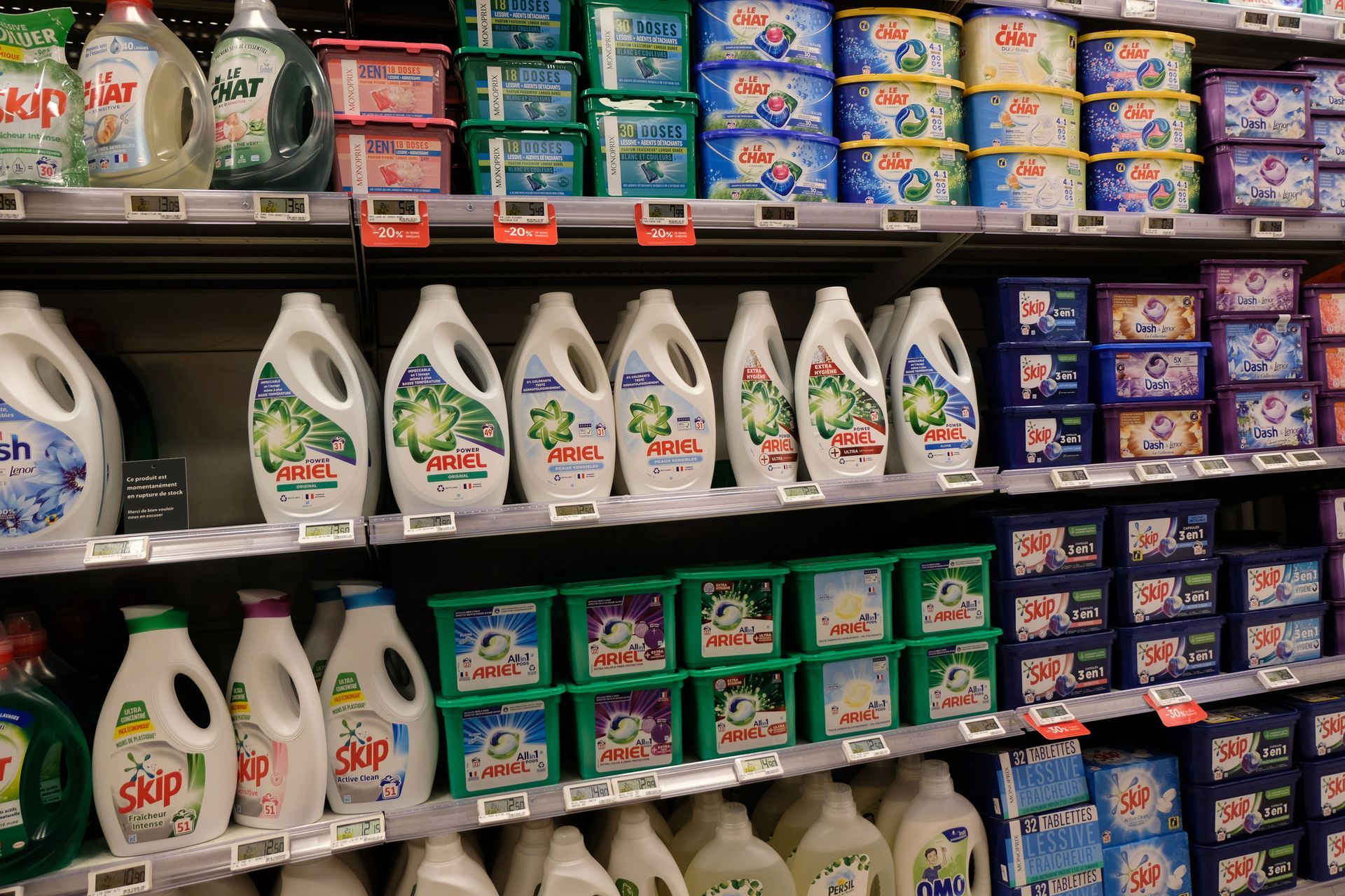 Estantes llenos de botellas y cajas de detergente en una tienda.