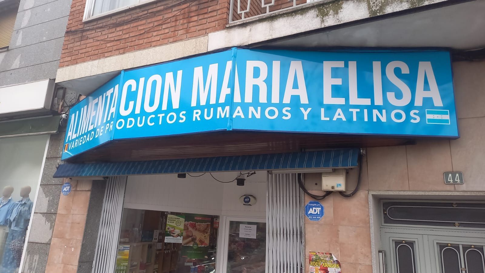 Estantes llenos de alimentos envasados ​​en una pequeña tienda, incluidos bocadillos, salsas y bebidas.
