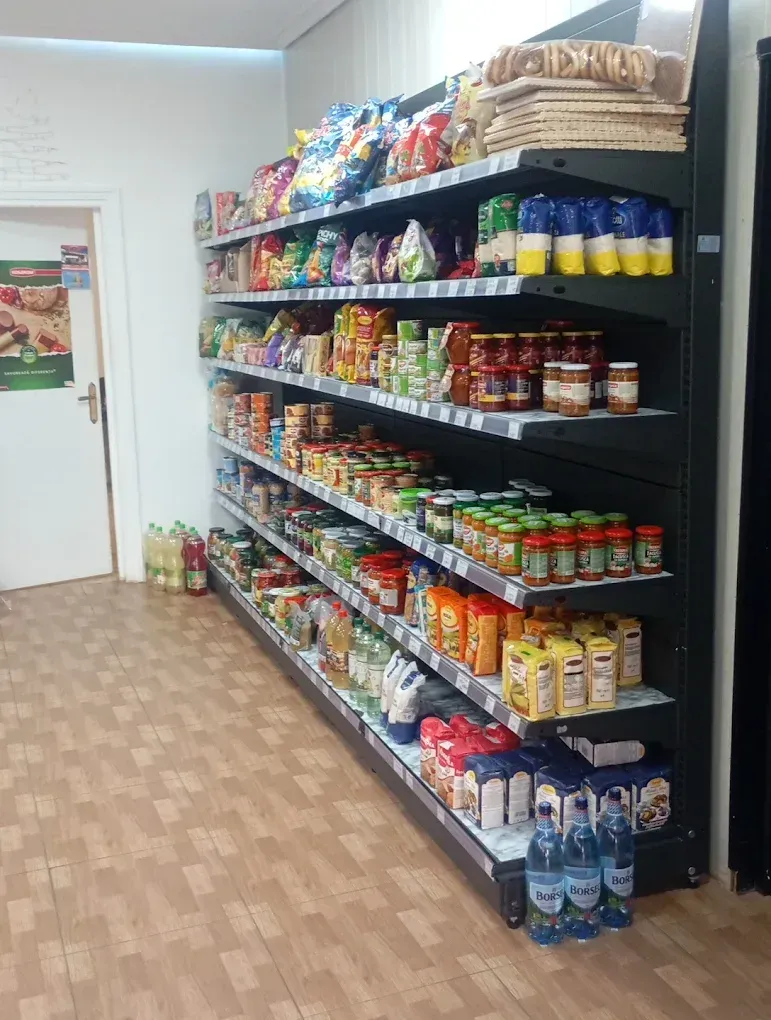 Estantes llenos de alimentos envasados ​​en una pequeña tienda, incluidos bocadillos, salsas y bebidas.