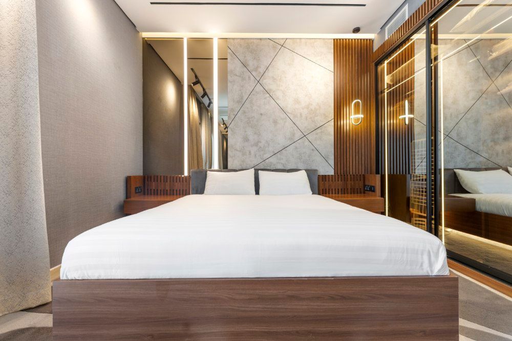 Modern bedroom with a large bed, wood accents, and marble-patterned wall panels