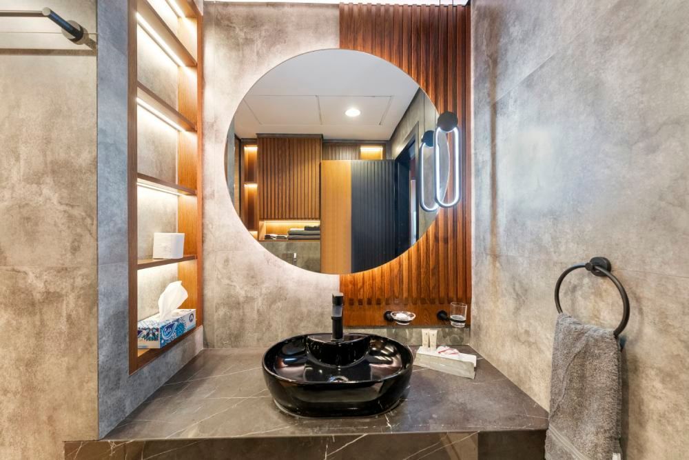 Modern bathroom vanity with round mirror, black sink, and wood accents