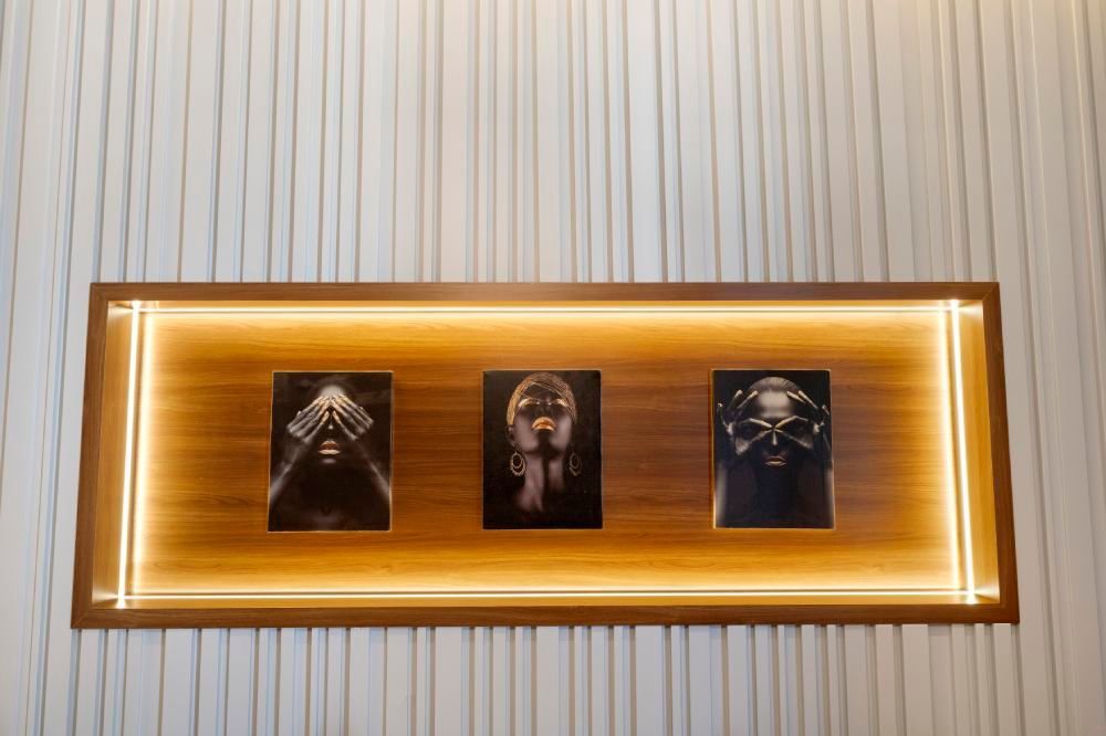 Framed wall display with warm backlighting and three dark portraits on a striped wall