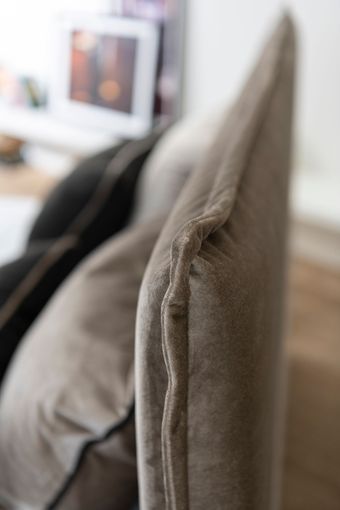 Nahaufnahme eines taupefarbenen Polsterkissens mit schwarzem Rand.