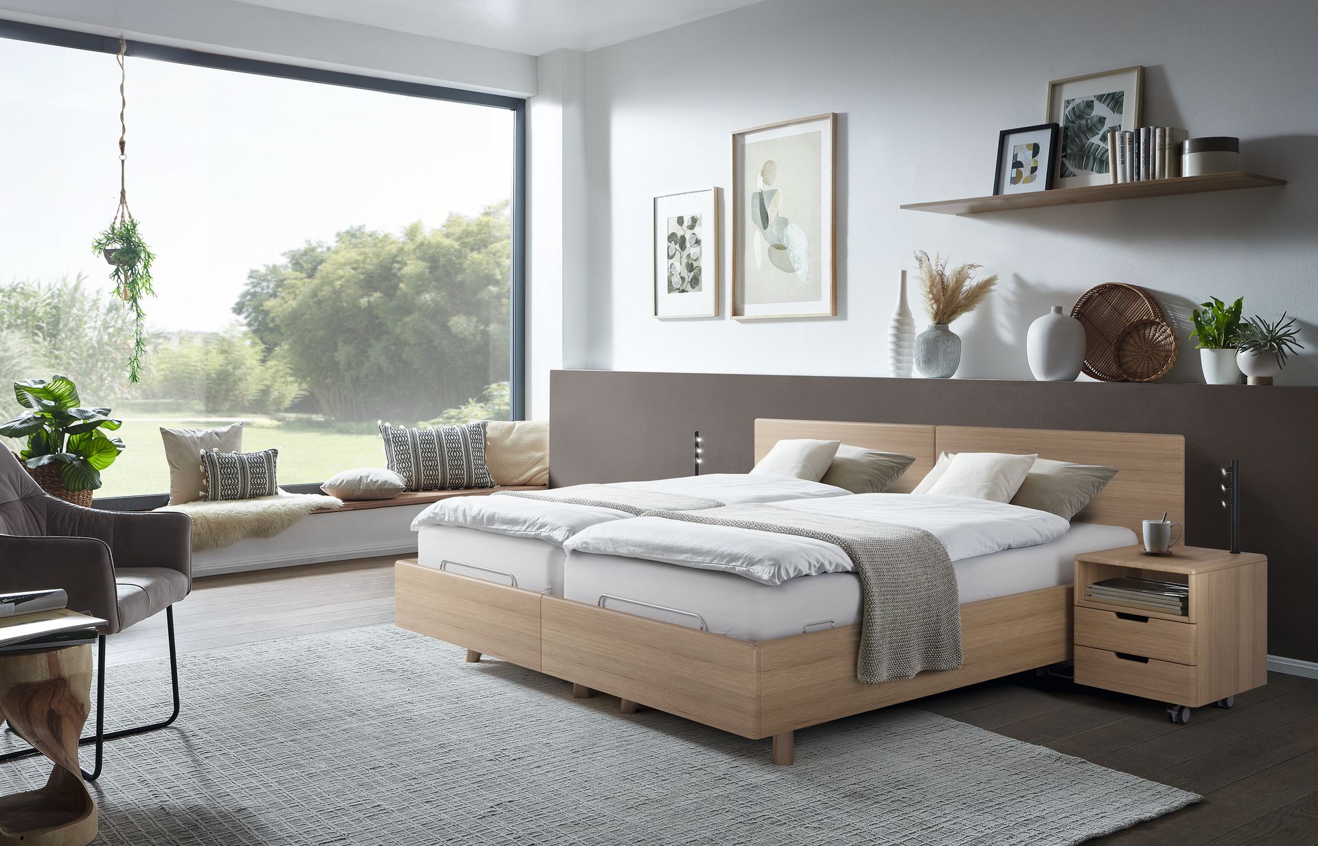 Schlafzimmer mit großem Fenster, Bett mit weißer Bettwäsche, hölzernem Nachttisch und Sitzecke.