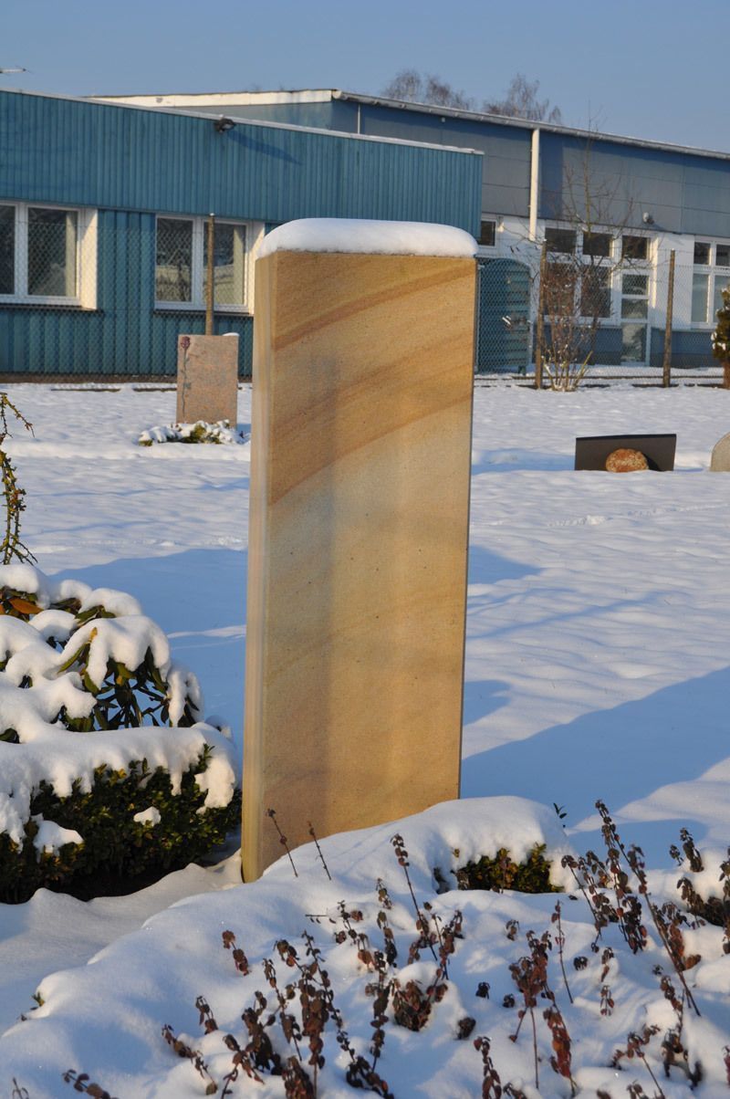 Eine Säule im Schnee mit einem blauen Gebäude im Hintergrund