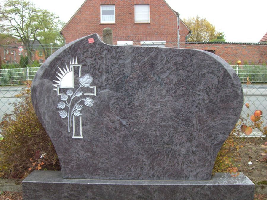 Ein Grabstein mit einem Kreuz und Blumen darauf