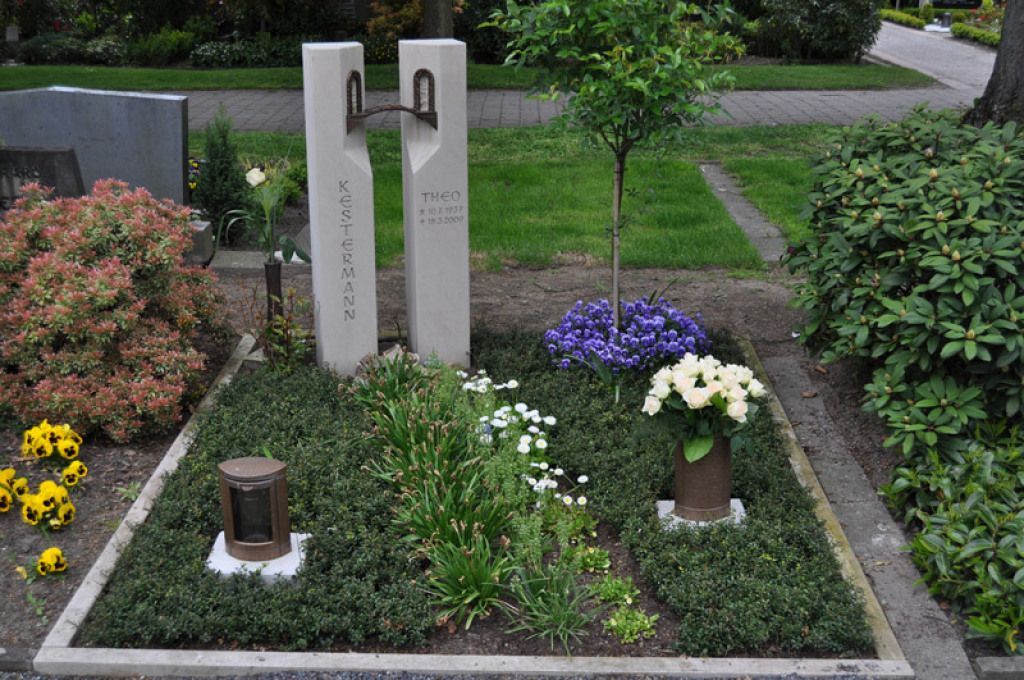 Ein Grab auf einem Friedhof mit Blumen und einem Baum