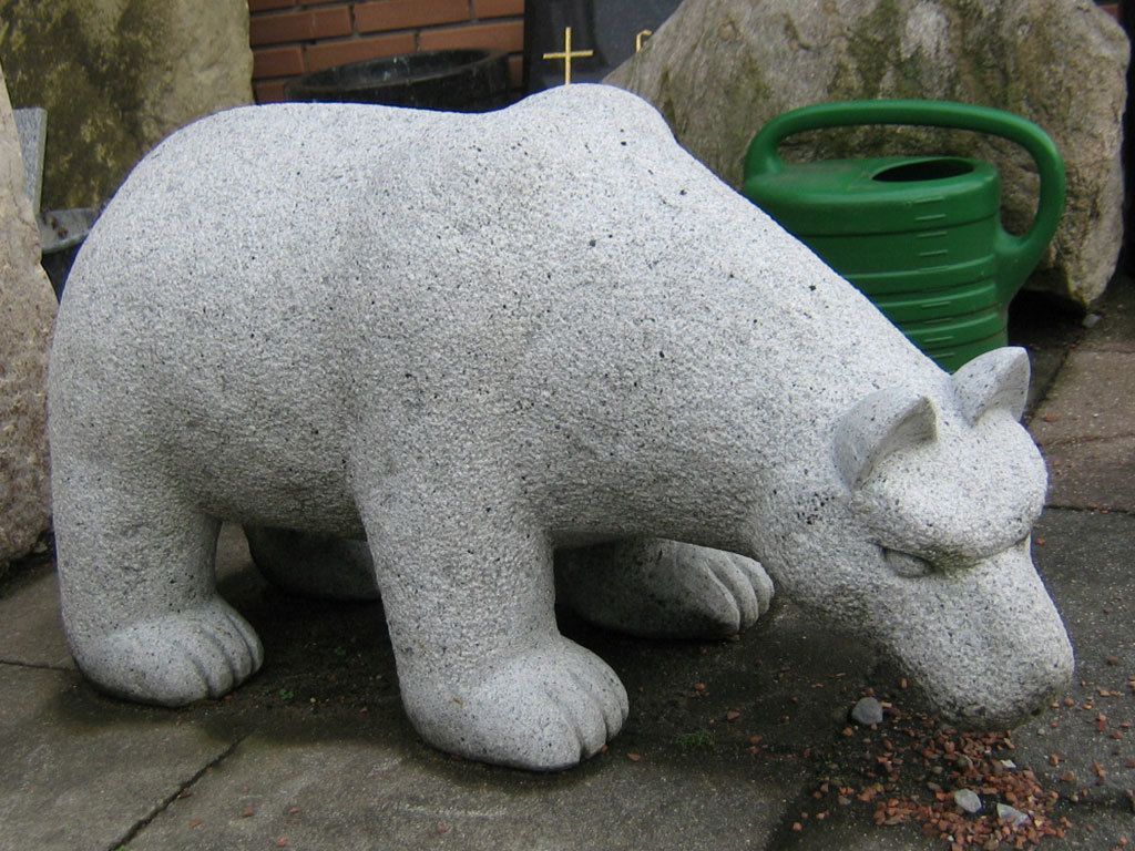 Eine Statue eines Eisbären neben einer grünen Gießkanne