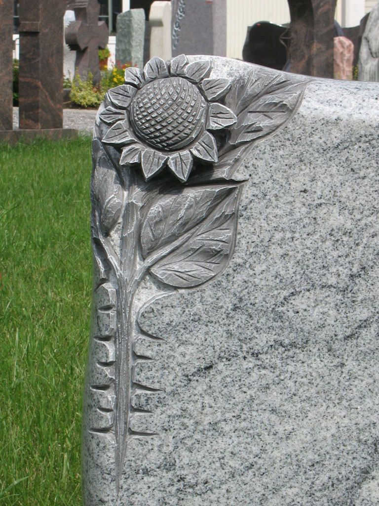 Ein Grabstein mit einer darin geschnitzten Sonnenblume.