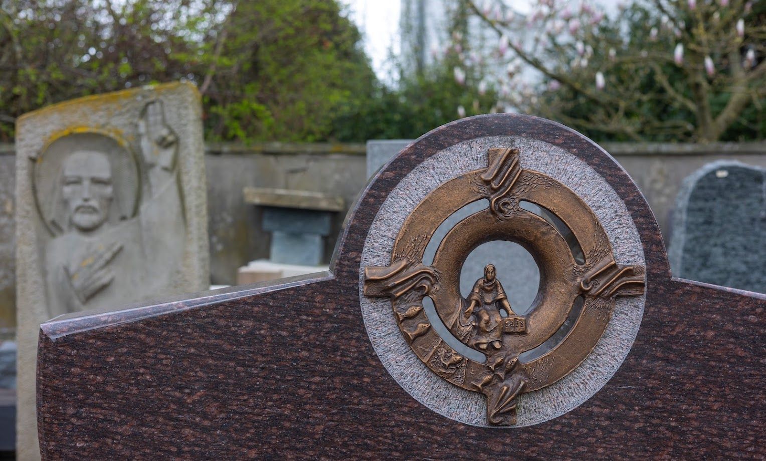 Ein Grabstein mit einem Kranz darauf auf einem Friedhof.
