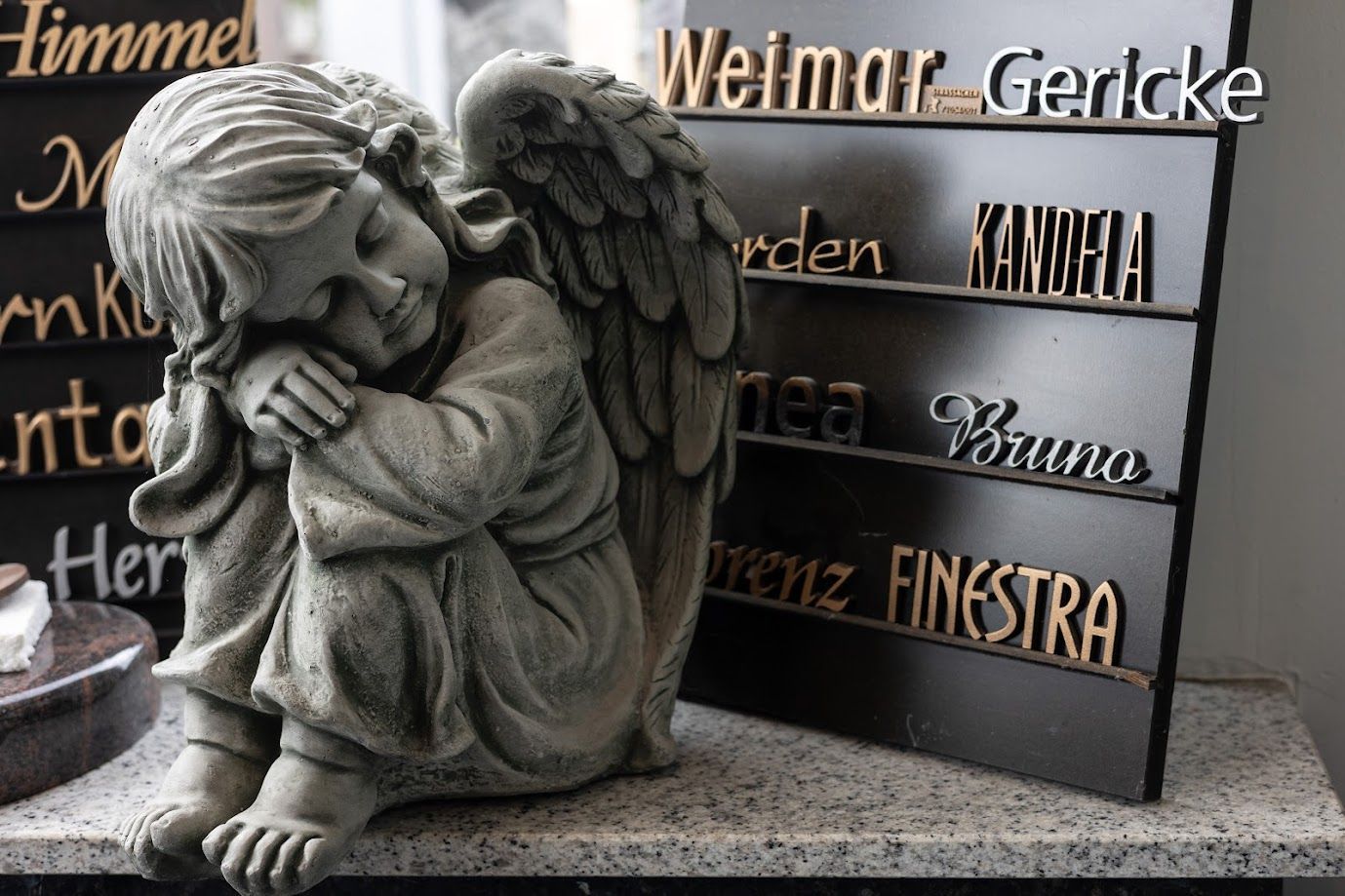 Neben einem Schild mit der Aufschrift „Weimar Gercke“ sitzt eine Engelsstatue