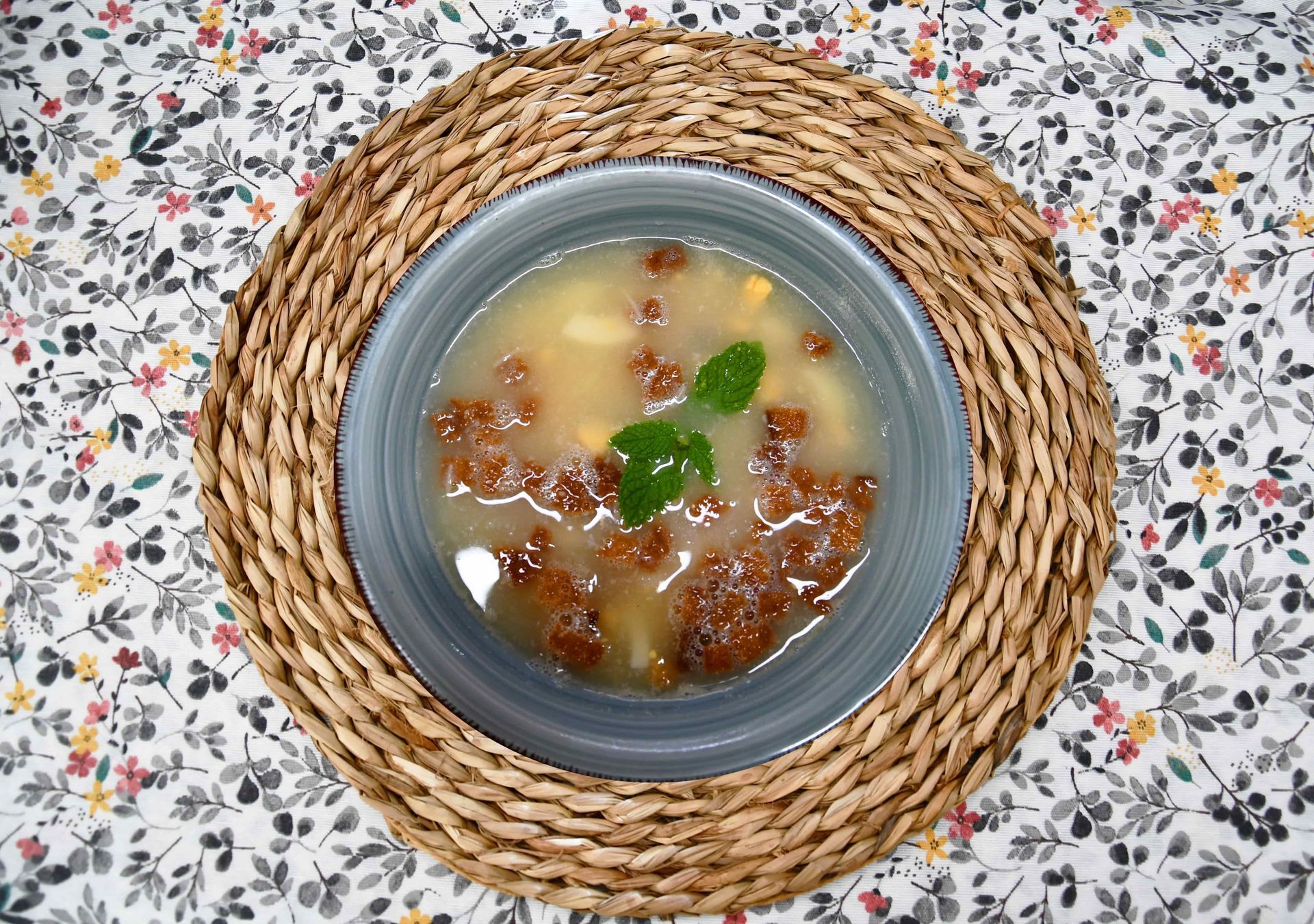 Un tazón de sopa está sobre un mantel sobre una mesa.