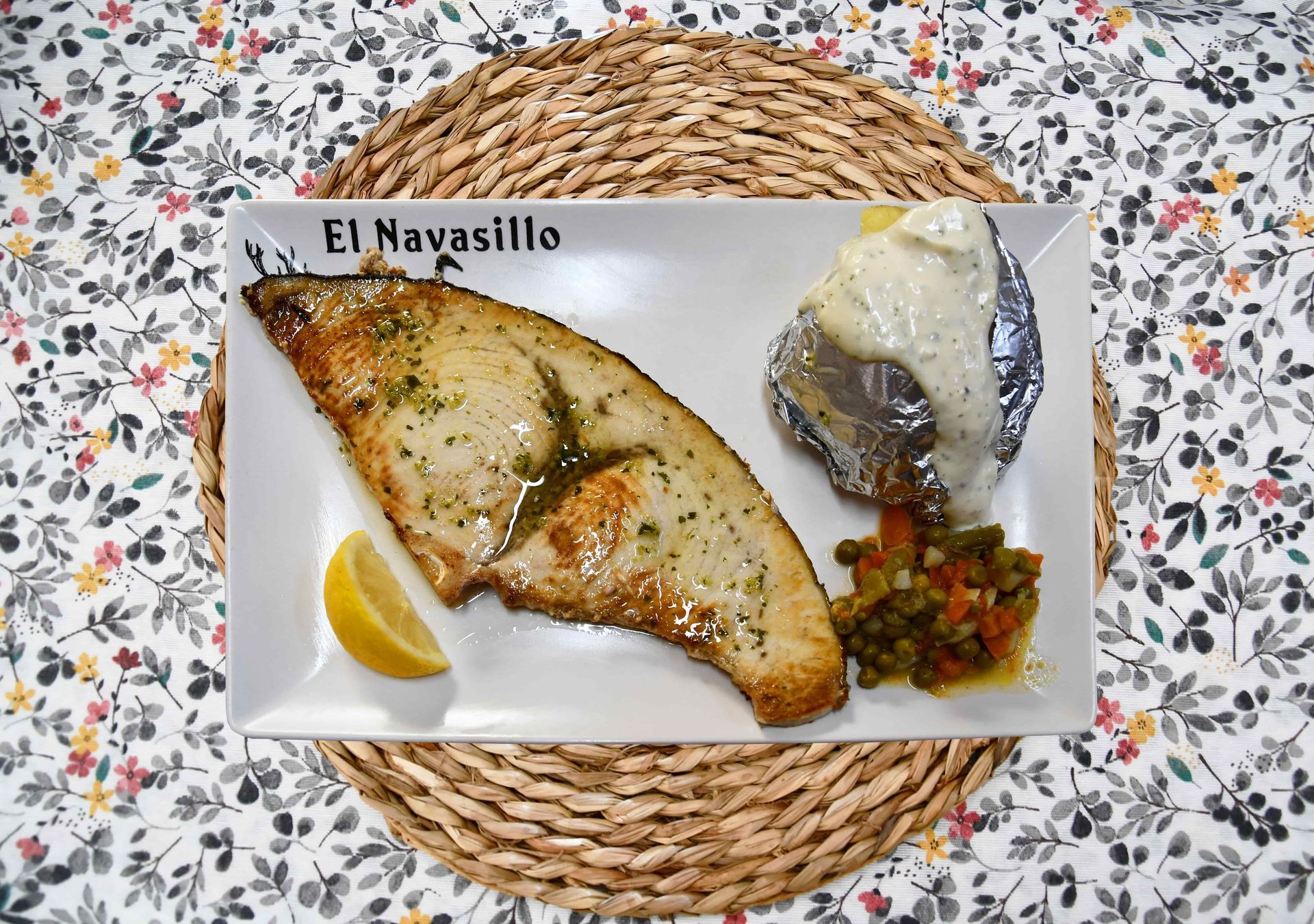 Un plato blanco con un trozo de pescado y patatas encima.