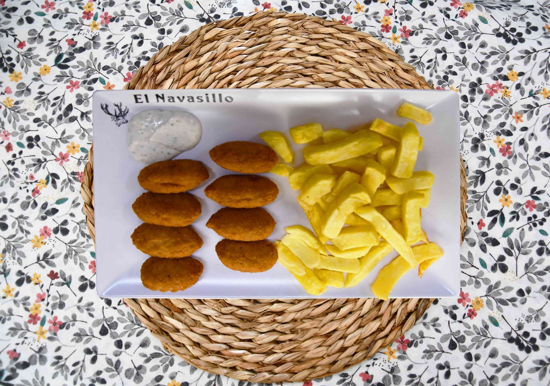 Un plato de comida con patatas fritas y nuggets en una mesa.