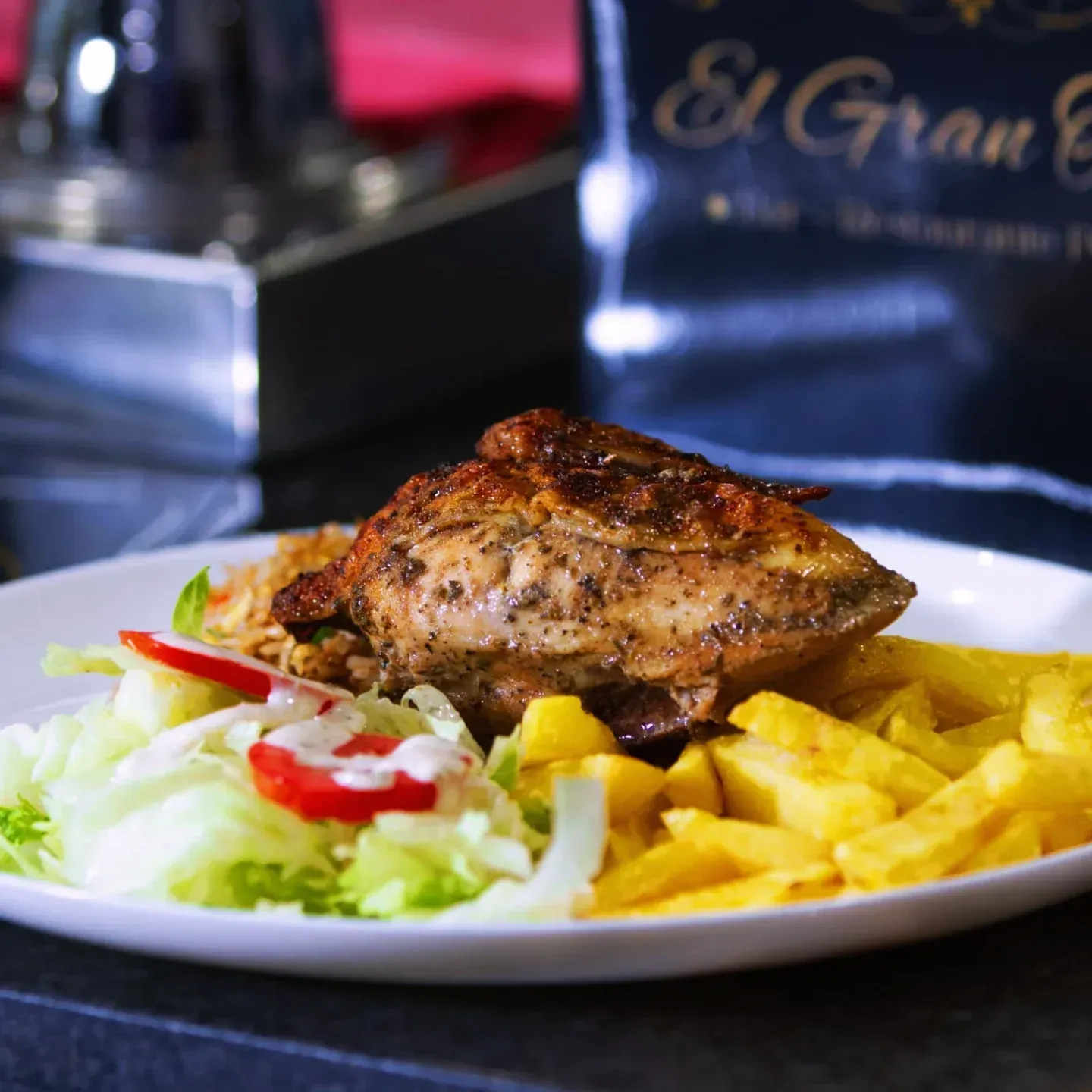 Plato de pollo a la parrilla, papas fritas, arroz y ensalada.